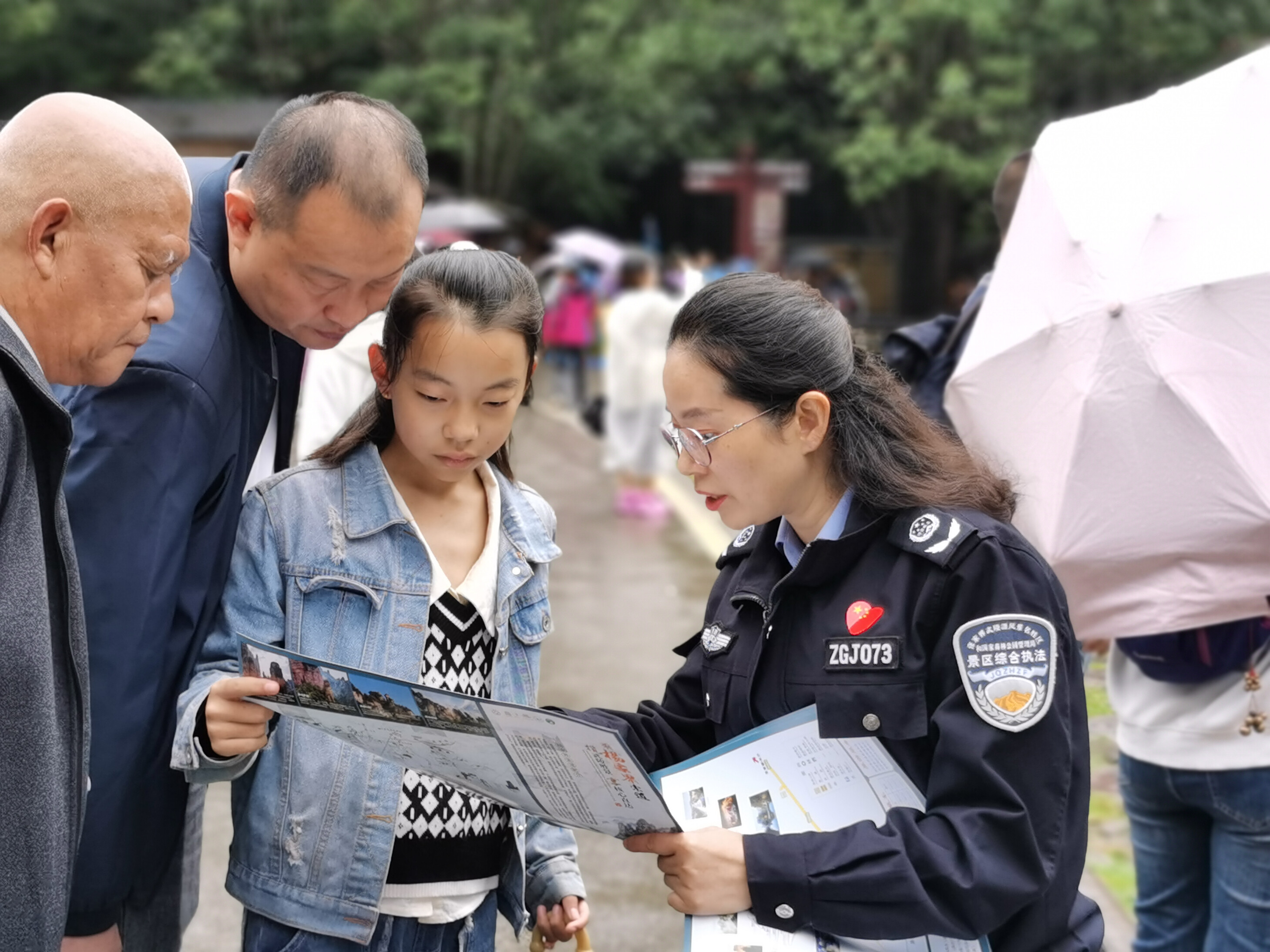 10月1日上年，金鞭溪景區(qū)管委會女子執(zhí)法隊隊員開展流動導覽服務，為游客免費贈送地圖。張娜 攝